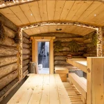 Traditional Russian banya at Anvil Fitness Club featuring natural log walls, wooden benches and warm lighting