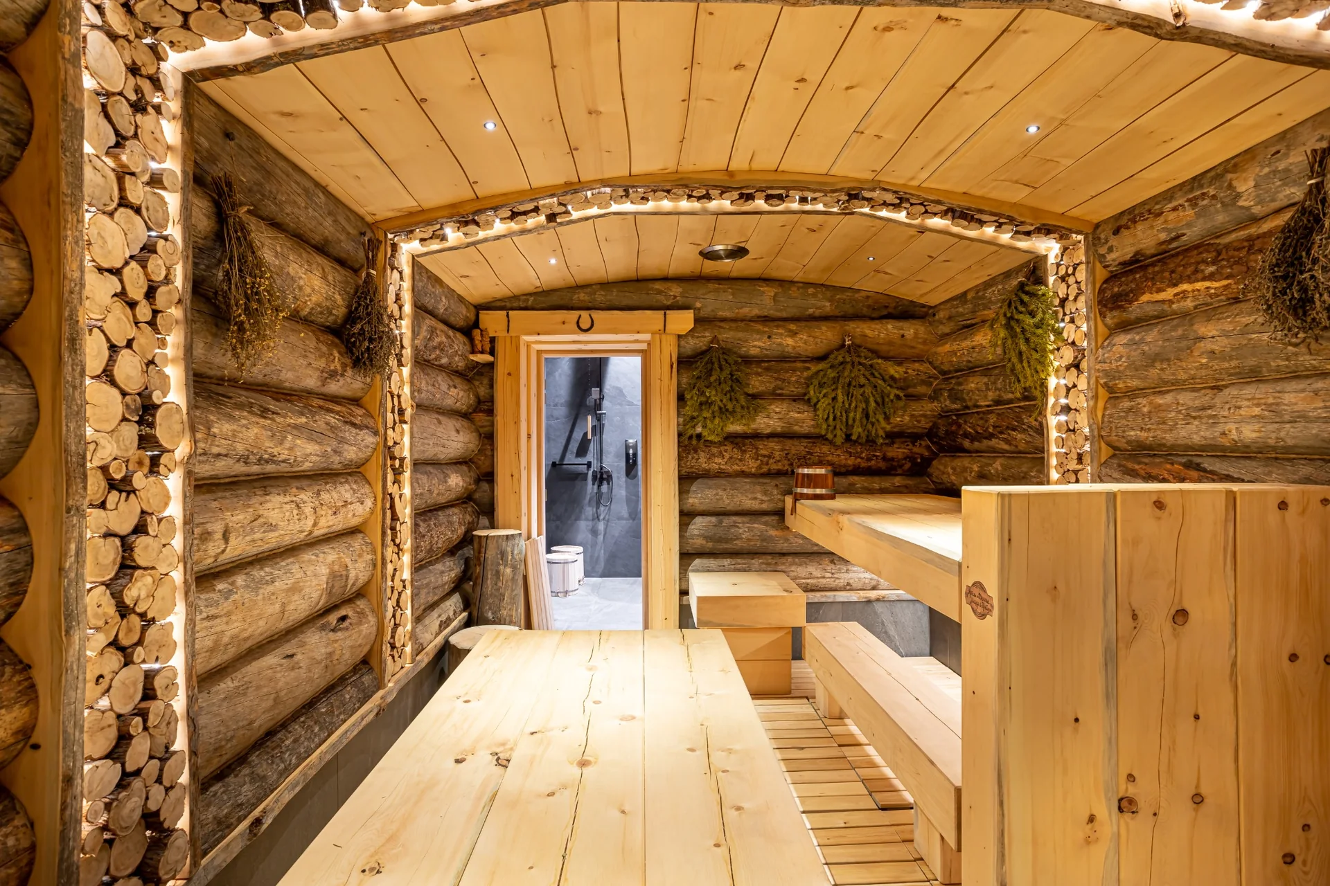 Traditional Russian banya at Anvil Fitness Club featuring natural log walls, wooden benches and warm lighting