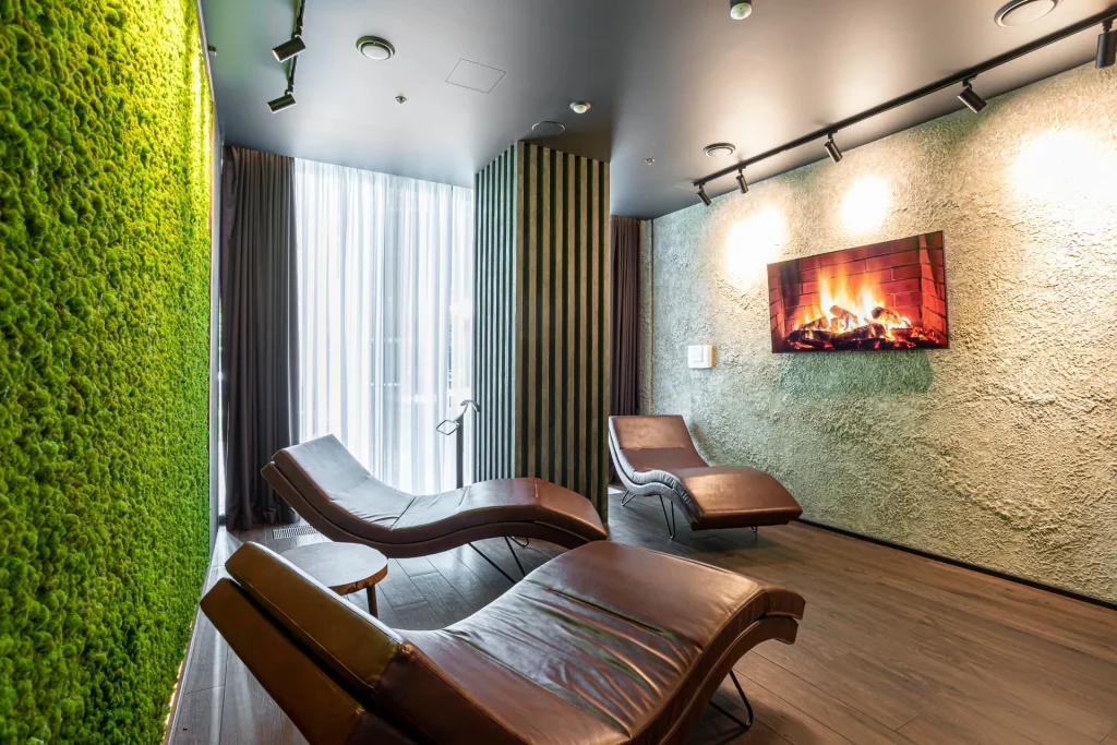 Premium wellness relaxation room at Anvil Fitness Club featuring leather loungers and a decorative fireplace