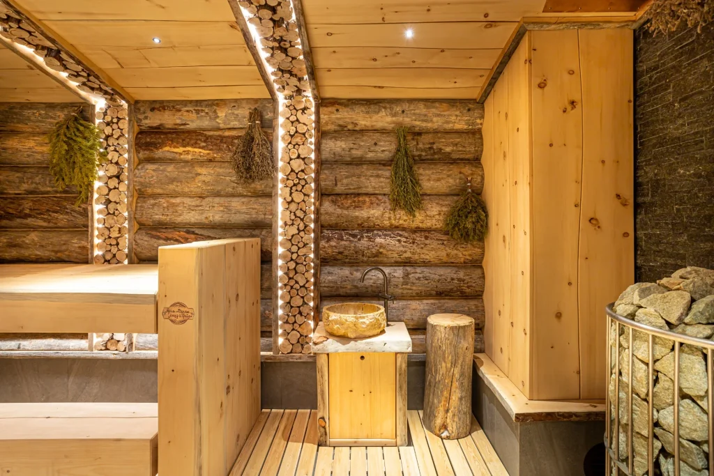 Russian banya steam room featuring a stone-filled sauna heater, wooden benches and natural log walls