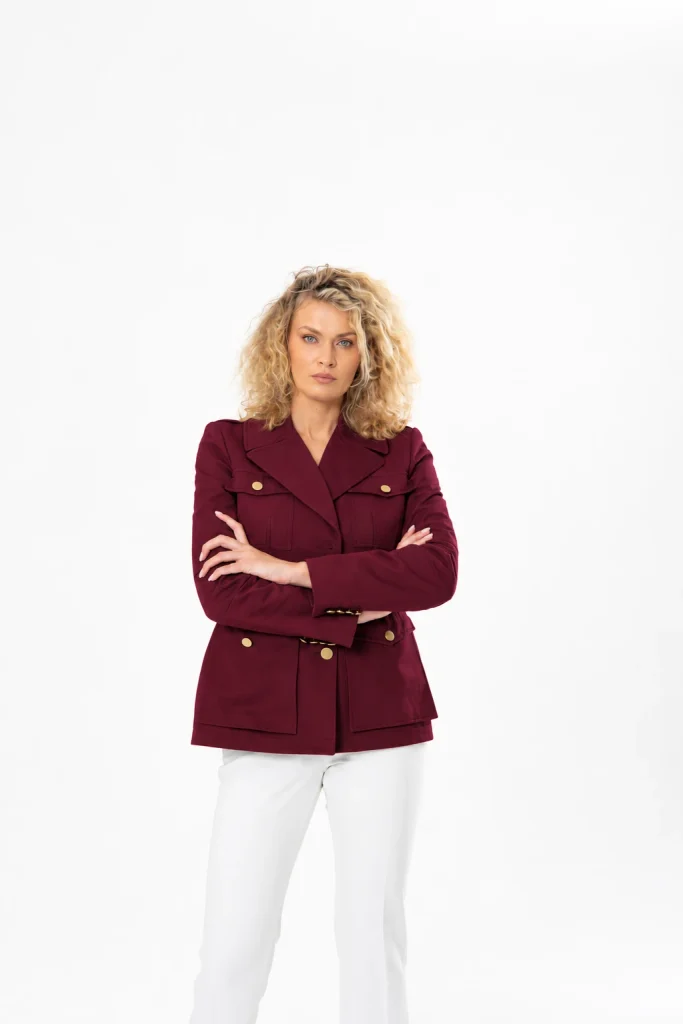 Nadezhda Grishaeva wearing a burgundy jacket with white trousers in a studio portrait