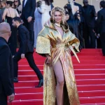 Nadezhda Grishaeva wearing a spectacular shimmering gold dress with a dramatic sculptural collar at Cannes 2026.
