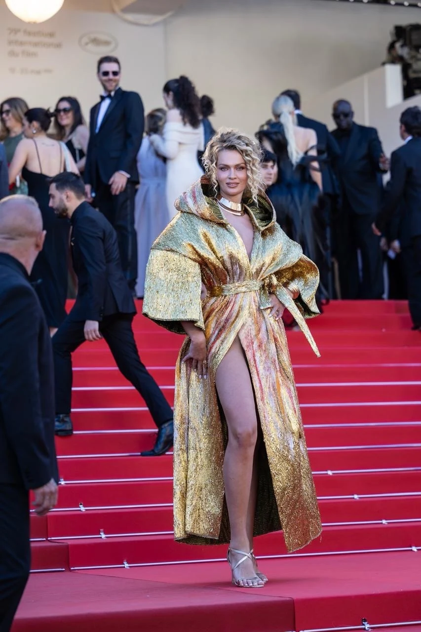 Nadezhda Grishaeva wearing a spectacular shimmering gold dress with a dramatic sculptural collar at Cannes 2026.