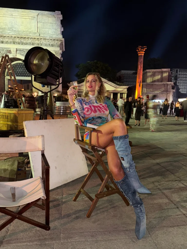 Nadezhda Grishaeva at an evening event in Rome, seated near a large film light and historic architecture