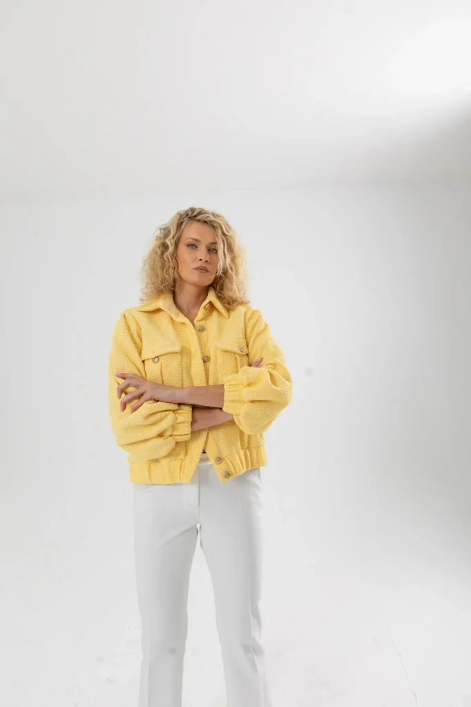 Nadezhda Grishaeva in a yellow textured jacket and white trousers in a studio portrait