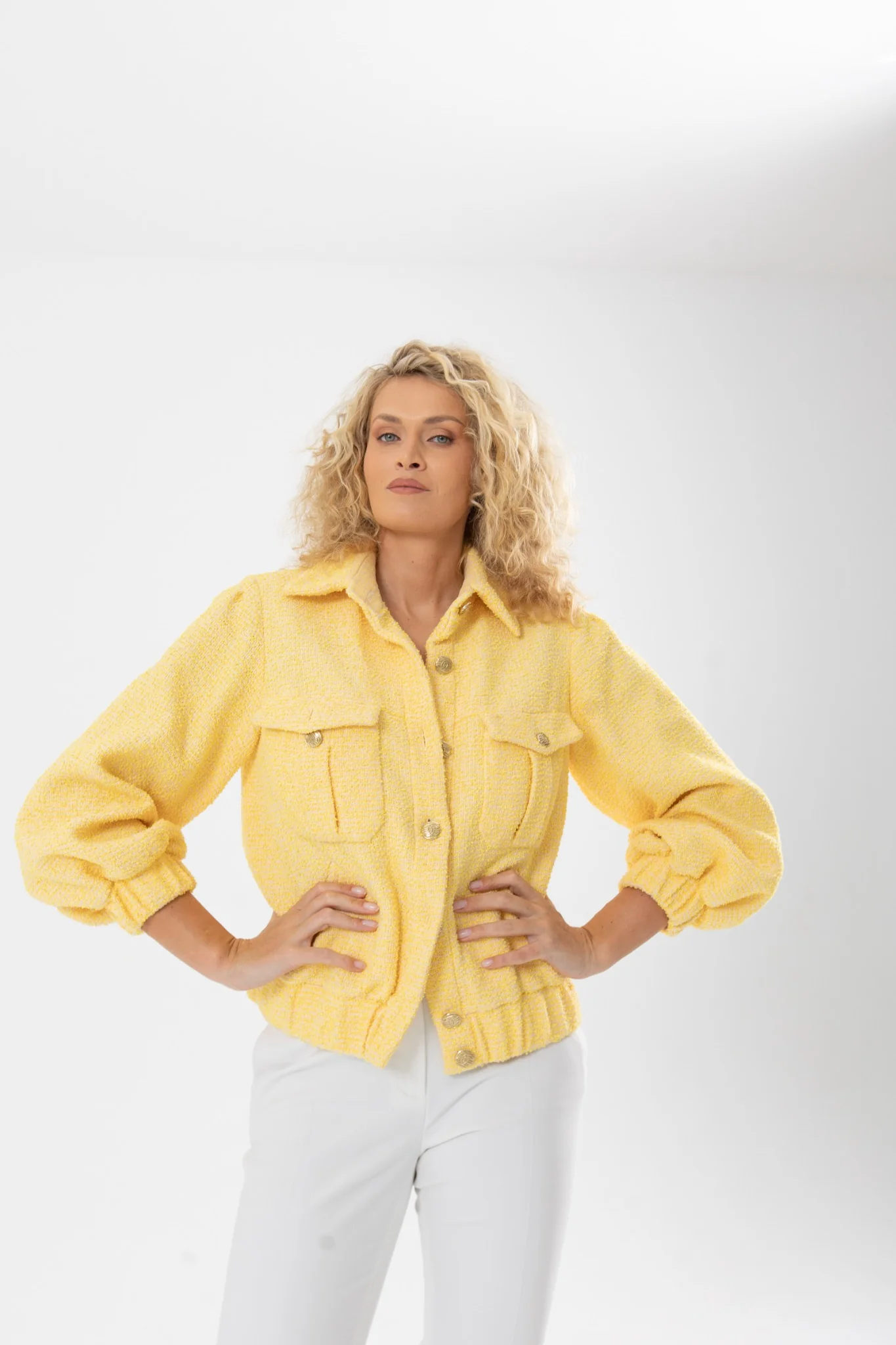 Nadezhda Grishaeva in a yellow textured jacket and white trousers in a studio portrait