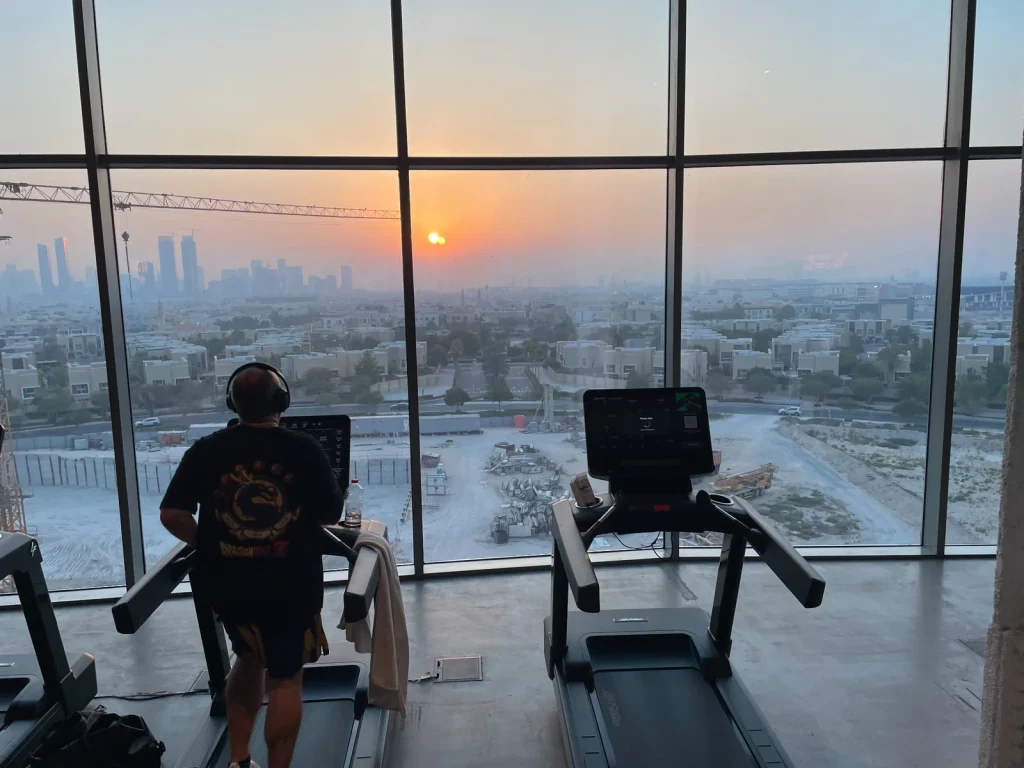 Cardio area at Warehouse Gym Dubai Science Park with floor-to-ceiling windows overlooking Dubai at sunset